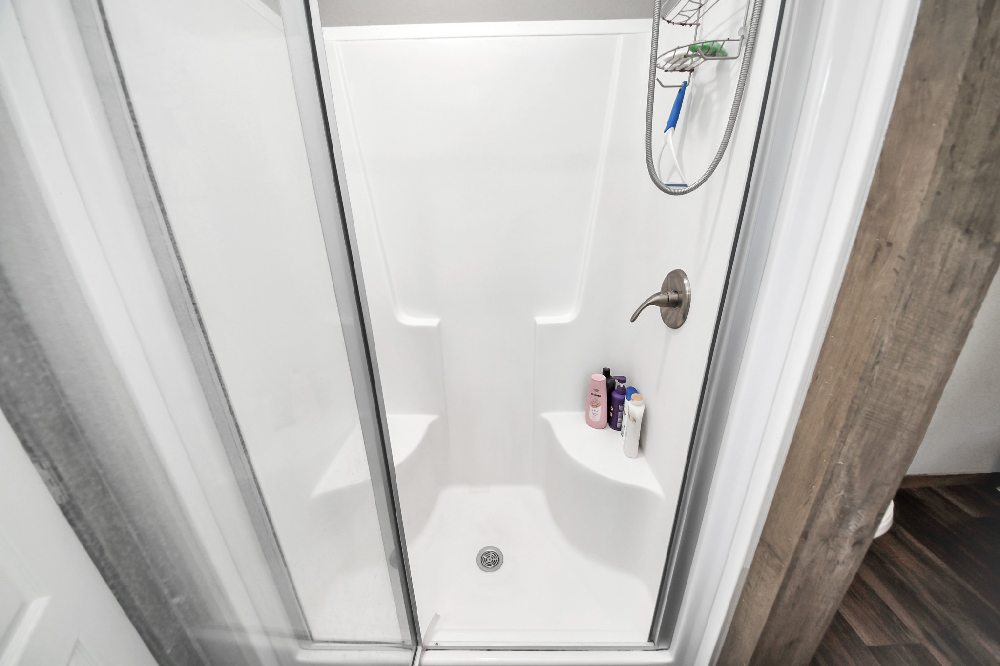 131 Kiowa Court Rosharon, TX 77583 - Photo 22 of 42 A compact shower stall with a glass door, white walls, and built-in corner shelving for toiletries.
