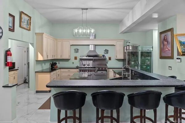 a kitchen with stainless steel appliances granite countertop a stove a refrigerator a sink a dining table and chairs with wooden floor