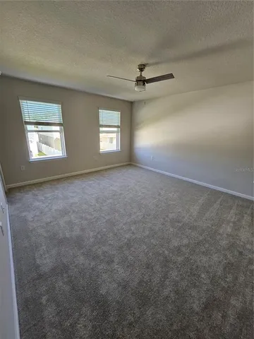 an empty room with windows and ceiling fan view