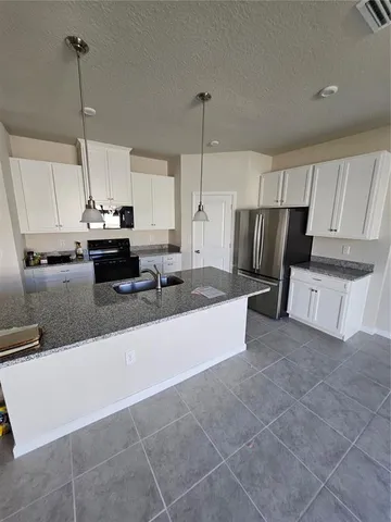 a kitchen with kitchen island granite countertop a stove a sink a counter top space and cabinets