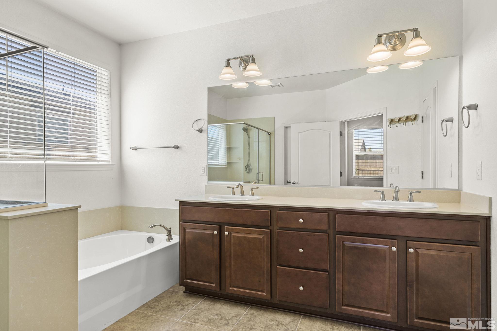 7360 Continuum Drive Reno, NV 89506 - Photo 18 of 28 a bathroom with a tub double vanity sink and mirror