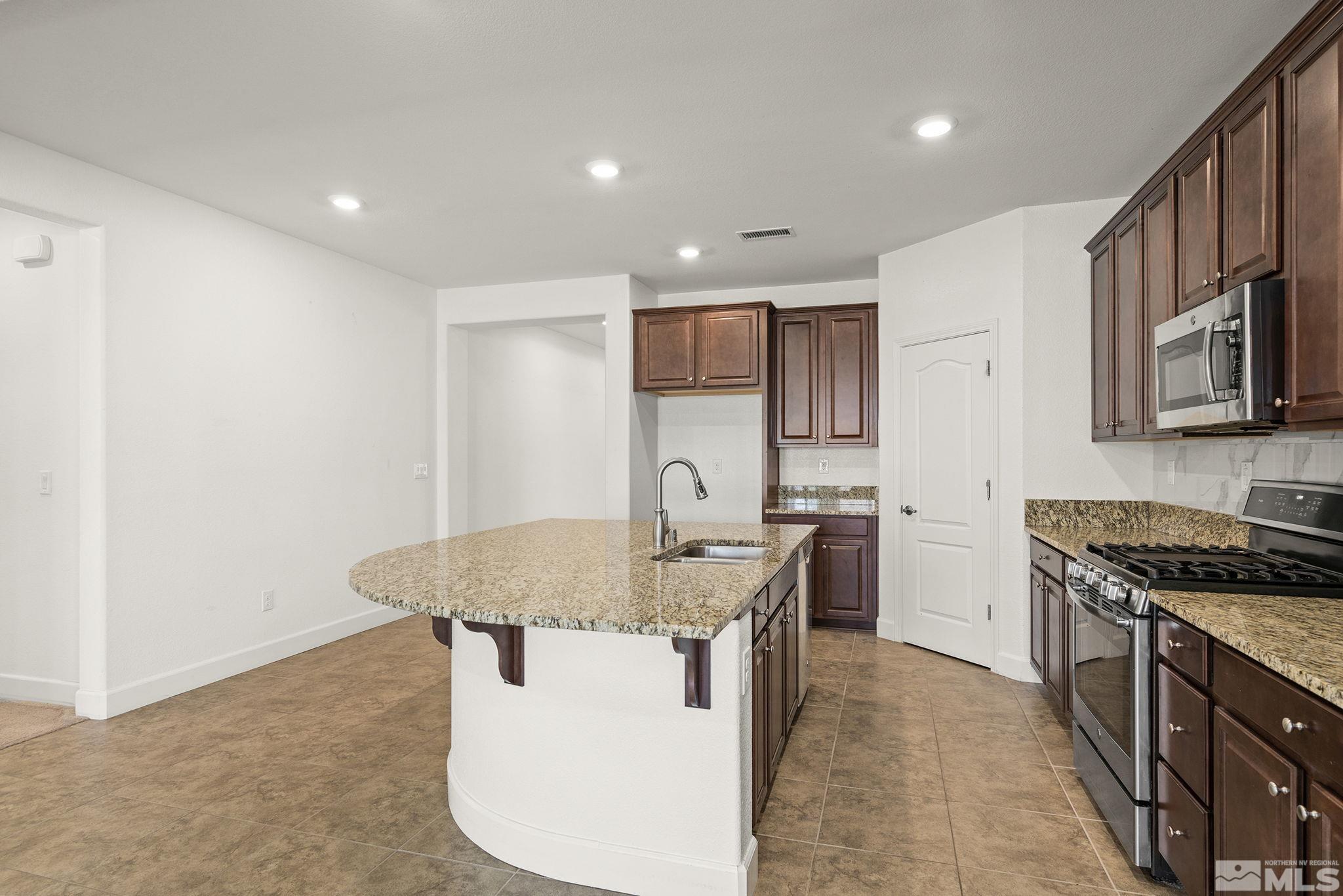 7360 Continuum Drive Reno, NV 89506 - Photo 8 of 28 a kitchen with stainless steel appliances granite countertop a sink stove and refrigerator