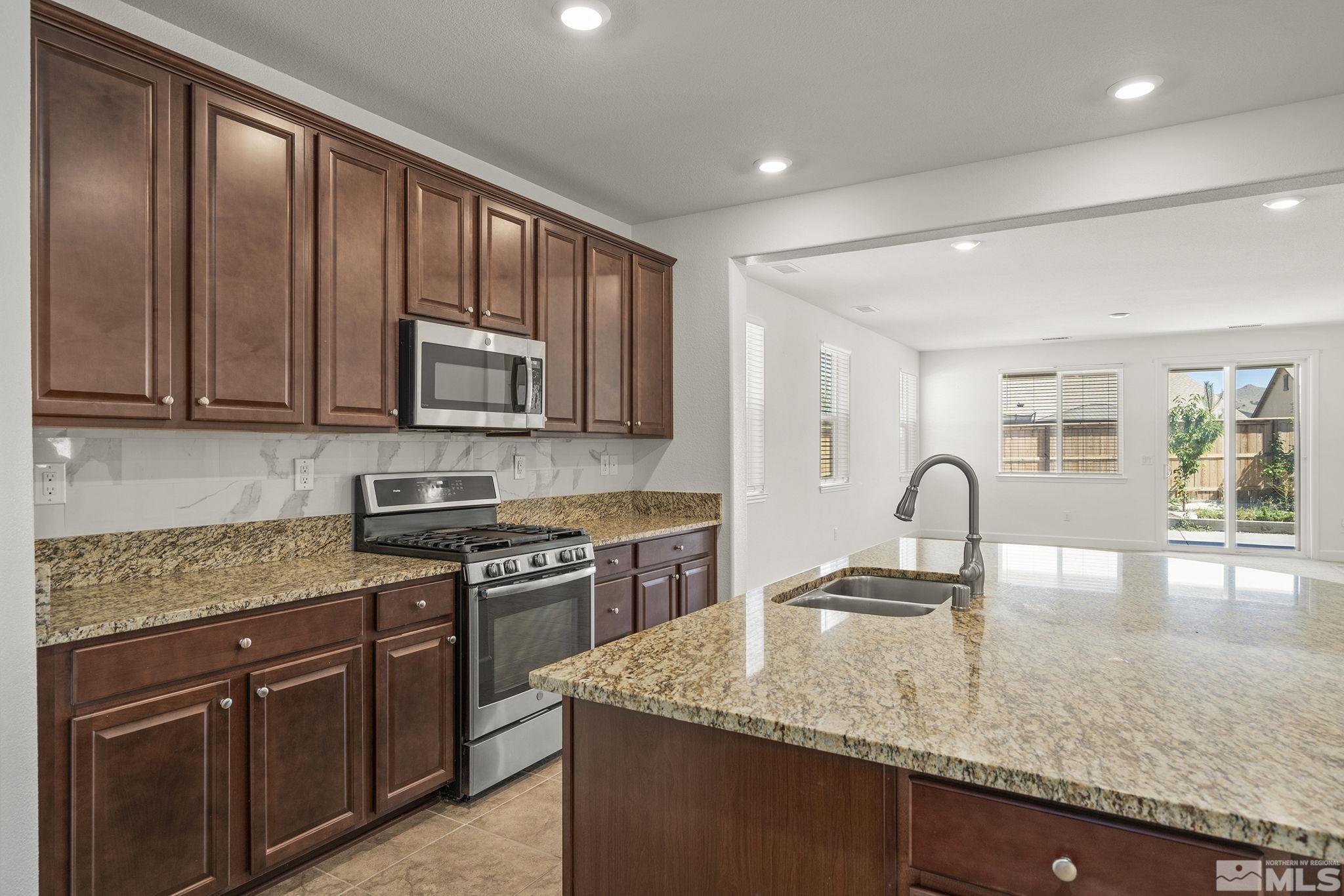 7360 Continuum Drive Reno, NV 89506 - Photo 9 of 28 a kitchen with granite countertop a stove top oven sink and cabinets