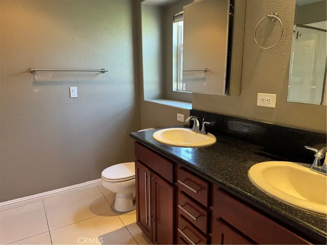 a bathroom with a granite countertop sink toilet and mirror