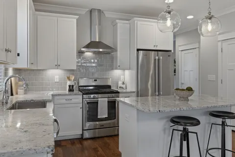 a kitchen with stainless steel appliances granite countertop a sink a stove and a refrigerator