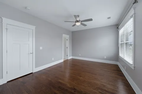 a view of empty room with wooden floor and fan
