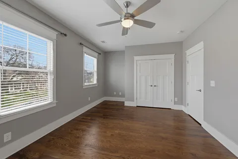 a view of an empty room with a window and wooden floor