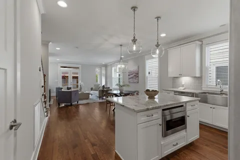 a open kitchen with sink stove and white cabinets with wooden floor