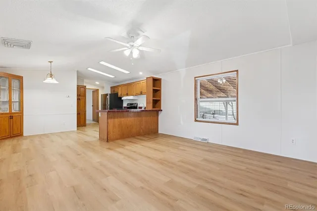 a view of an empty room with kitchen and a window