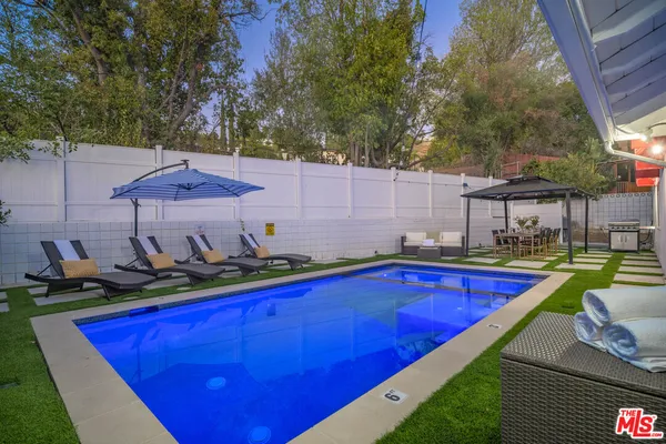 a view of a backyard with swimming pool and furniture