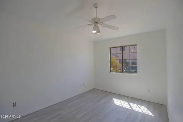 an empty room with wooden floor windows and fan