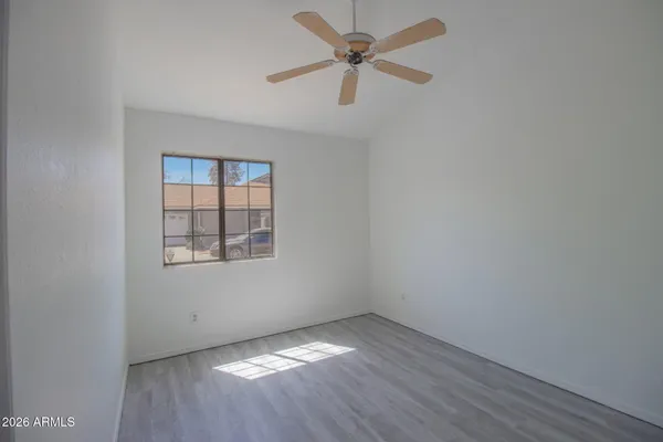 an empty room with wooden floor ceiling fan and windows