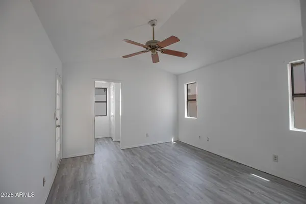 an empty room with wooden floor ceiling fan and windows