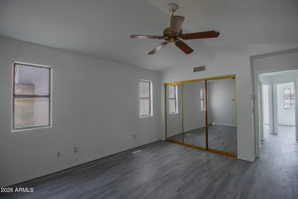 a view of empty room with wooden floor and fan