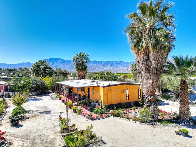 a backyard of a house with a table and chairs under an umbrella