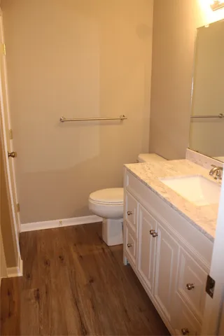 a bathroom with a sink a toilet and wooden floor