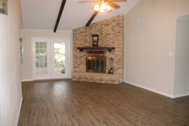 an empty room with wooden floor fireplace and windows