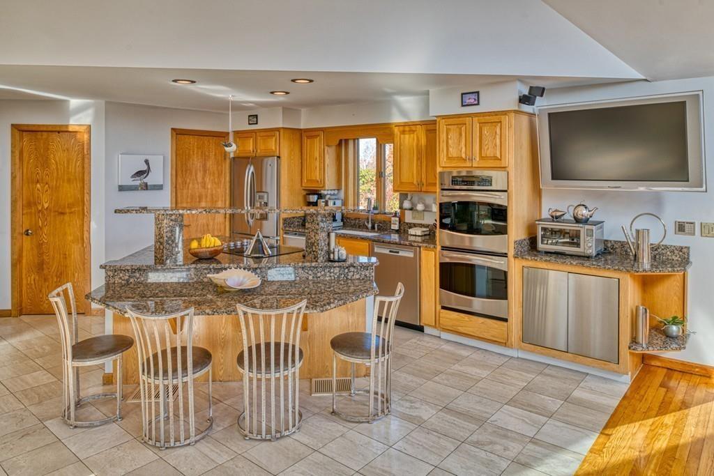 13 McKinley Road Marblehead, MA 01945 - Photo 9 of 36 a kitchen with stainless steel appliances granite countertop a stove top oven a sink a dining table and chairs