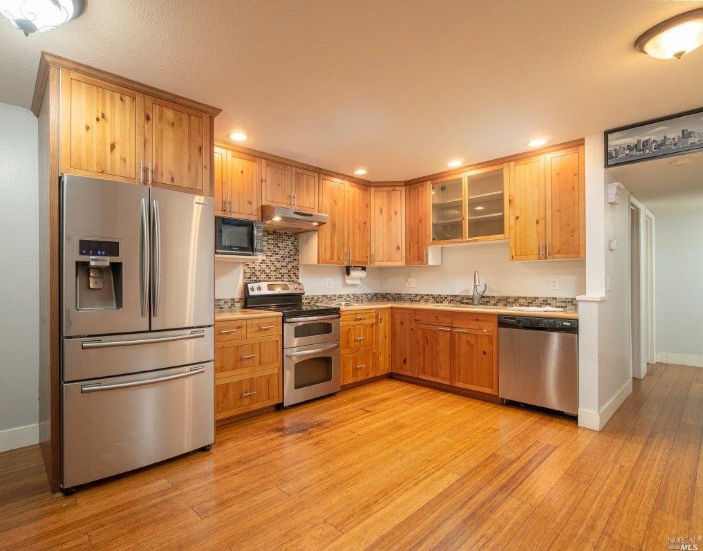 a kitchen with granite countertop a refrigerator and wooden floors