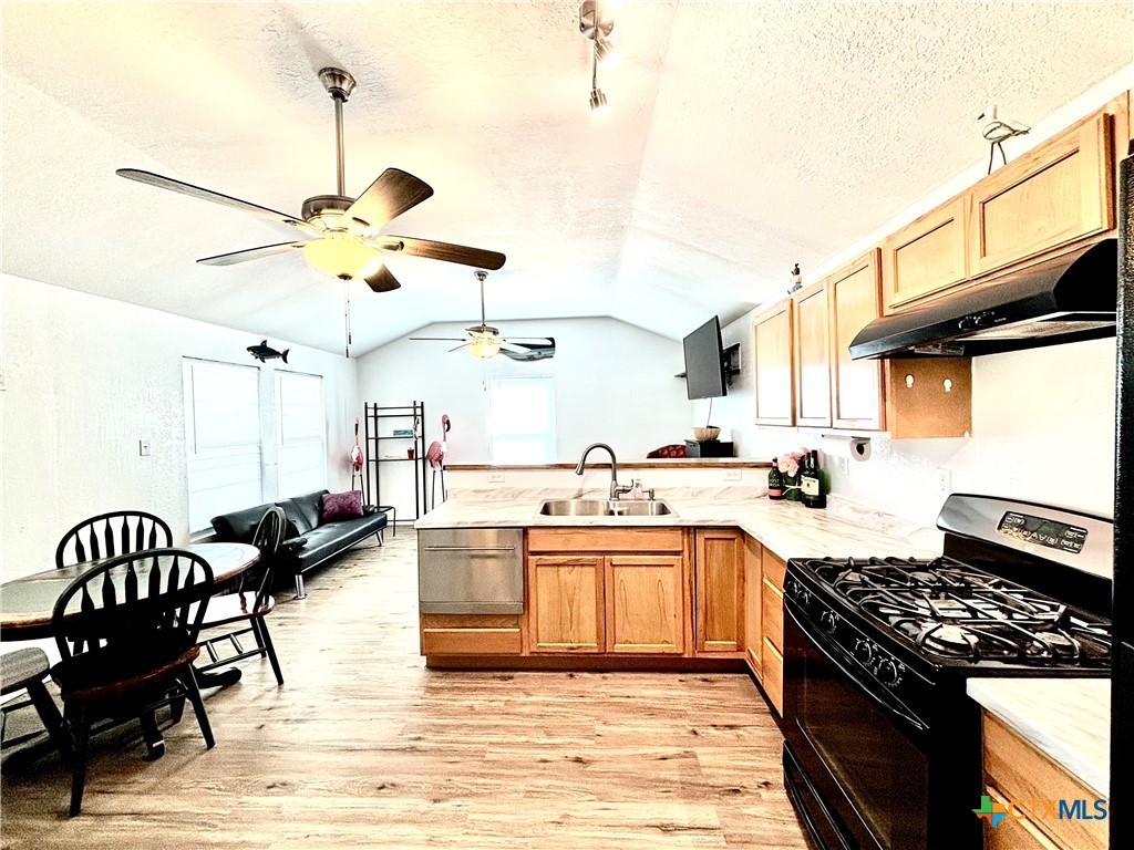 101 13th Street Seadrift, TX 77983 - Photo 21 of 42 a kitchen with stainless steel appliances granite countertop a stove a sink a dining table and chairs with wooden floor