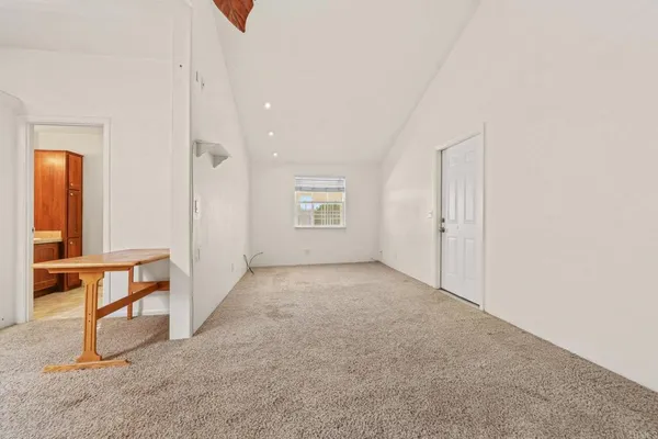 a view of an empty room with chandelier fan and fire place