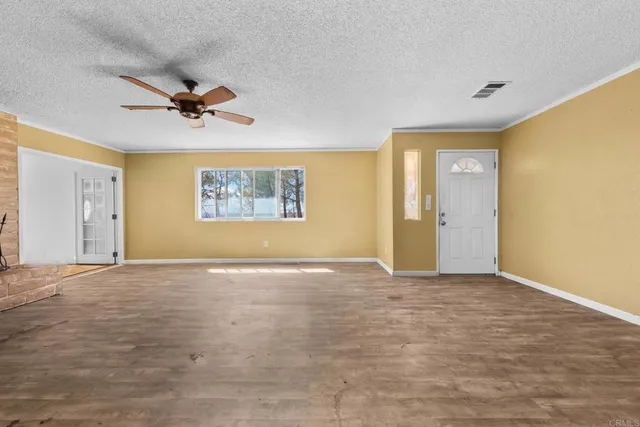 an empty room with a ceiling fan and window