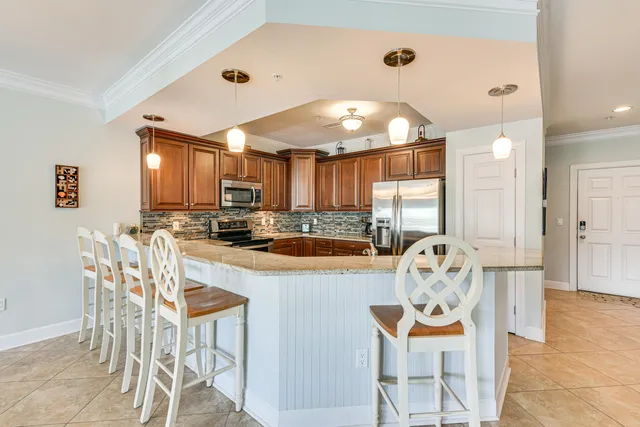 a kitchen with stainless steel appliances kitchen island granite countertop a dining table chairs and white cabinets