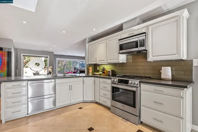 a kitchen with granite countertop white cabinets stainless steel appliances and sink