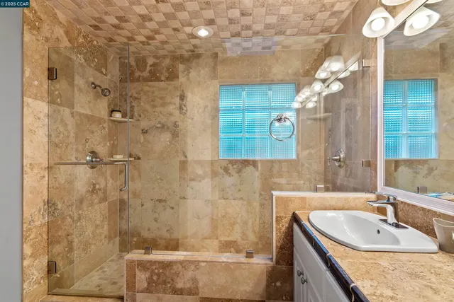 a bathroom with a granite countertop shower a sink and a mirror