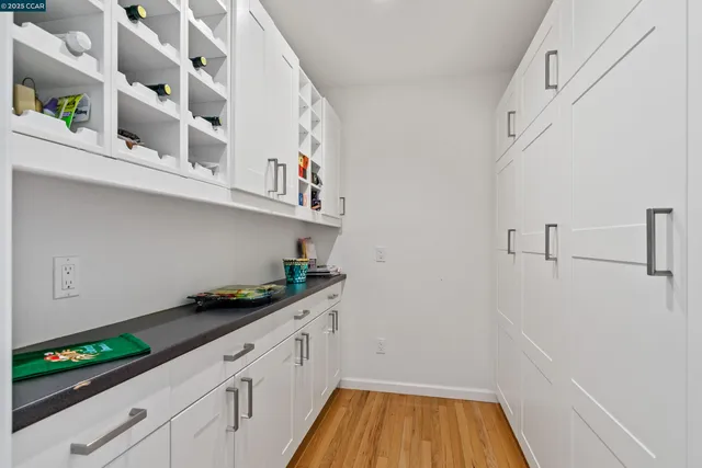 a kitchen with white cabinets and wooden floor