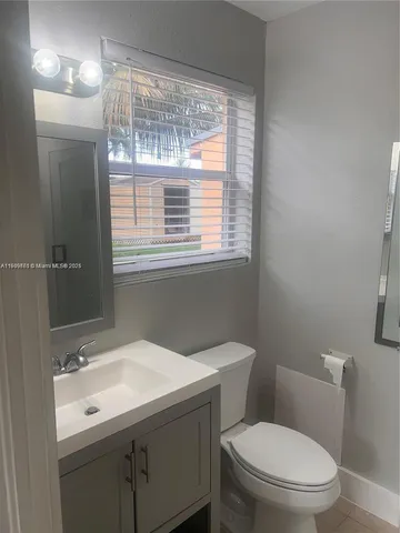 a bathroom with a sink a toilet a mirror and a window