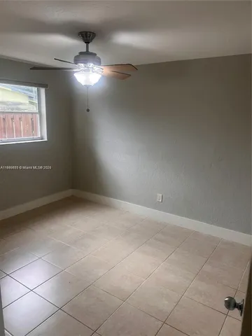 en empty room with windows and chandelier fan