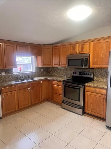 a kitchen with granite countertop a stove top oven microwave and cabinets