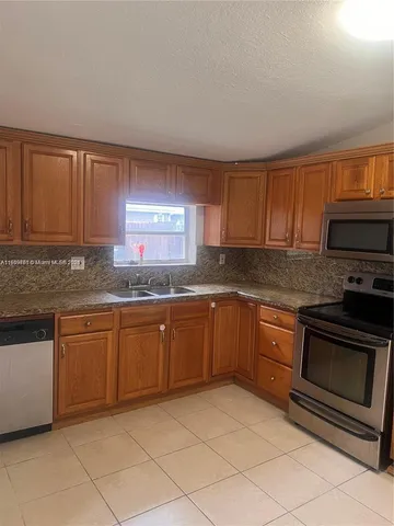 a kitchen with granite countertop a sink cabinets and stainless steel appliances