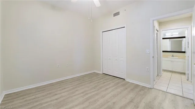 a view of an empty room with closet and mirror