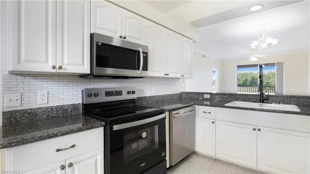 a kitchen with granite countertop white cabinets and a stove top oven