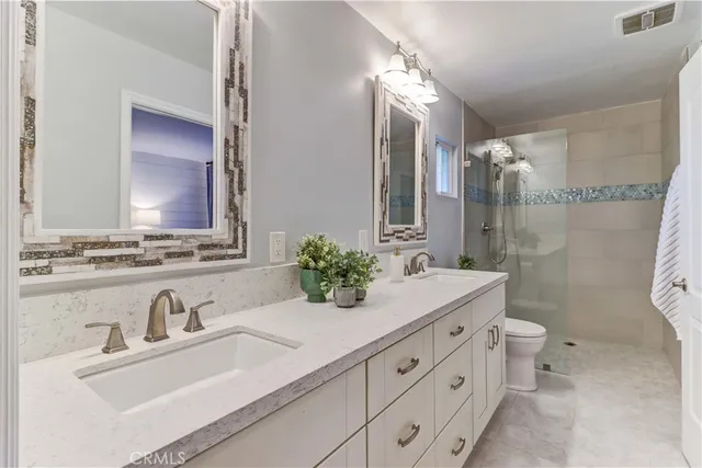 a bathroom with a double vanity sink mirror and toilet