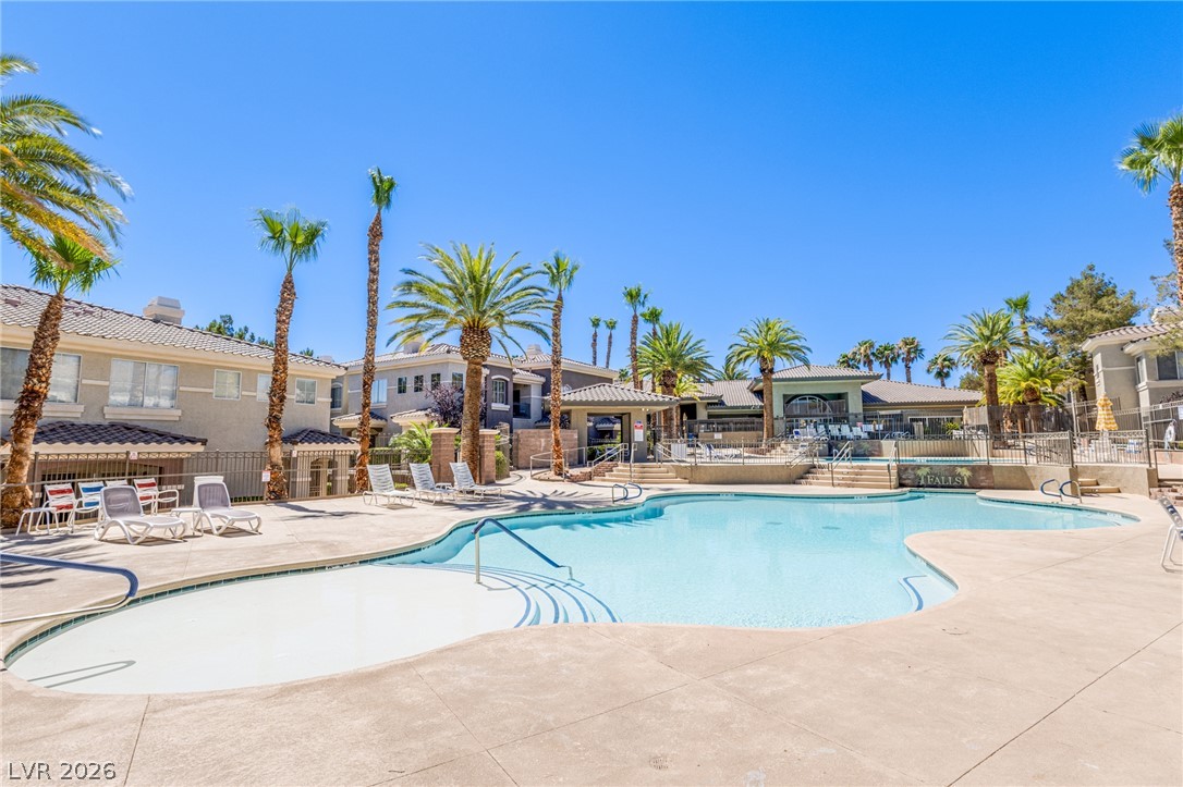 9050 West Warm Springs Road, Unit 1011 Las Vegas, NV 89148 - Photo 25 of 32 A spacious, freeform pool provides an inviting oasis amidst verdant palm trees and residential structures.