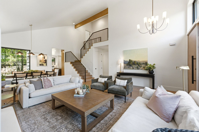3027 Homestead Road Park City, UT 84098 - Photo 4 of 62 Vaulted ceiling living area featuring wood-finish flooring, a contemporary chandelier, and a prominent staircase with black metal railings