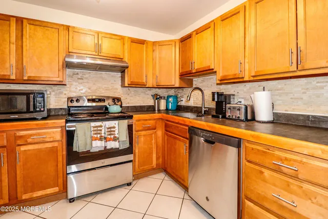 a kitchen with stainless steel appliances granite countertop a stove a sink and a microwave