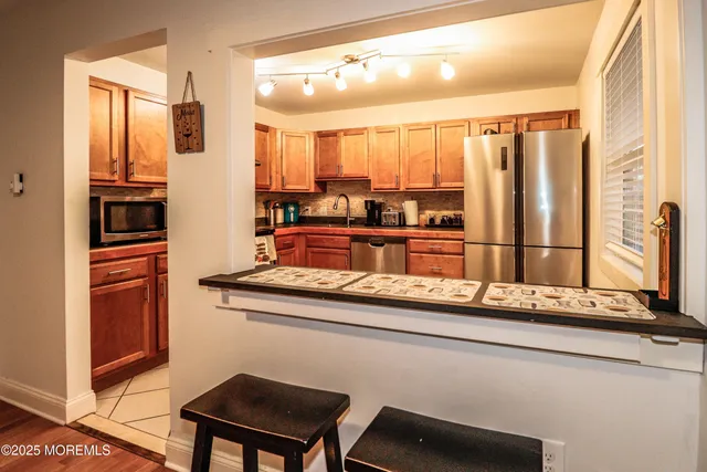 a view of a kitchen with kitchen island granite countertop a sink and a refrigerator