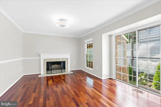 an empty room with wooden floor fireplace and windows