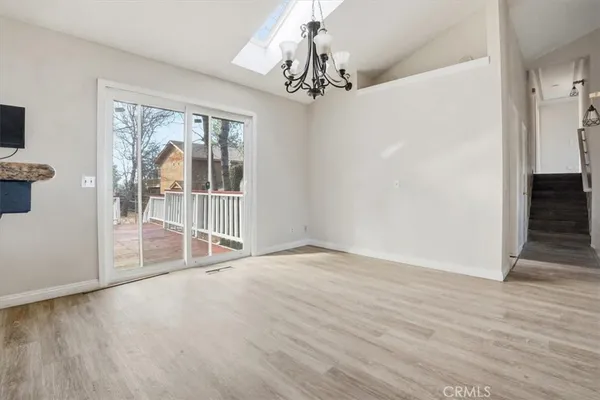 a view of an empty room with window and wooden floor