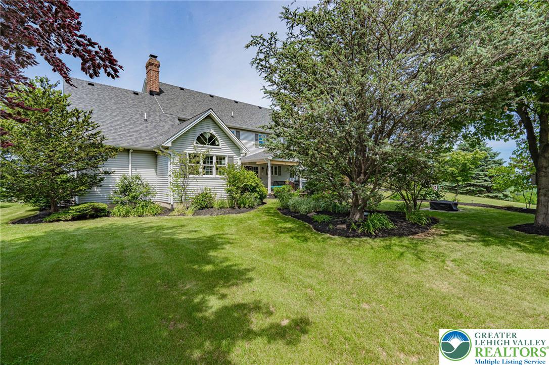 4542 Springfield Drive Coplay, PA 18037 - Photo 75 of 89 A well-maintained lawn wraps around a charming residence, framed by mature trees and lush landscaping.