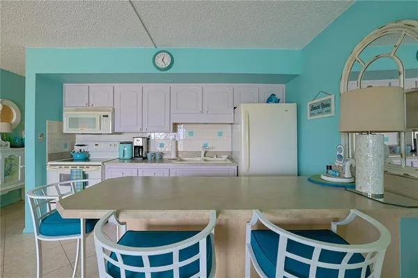 a kitchen with stainless steel appliances granite countertop a table chairs and a refrigerator
