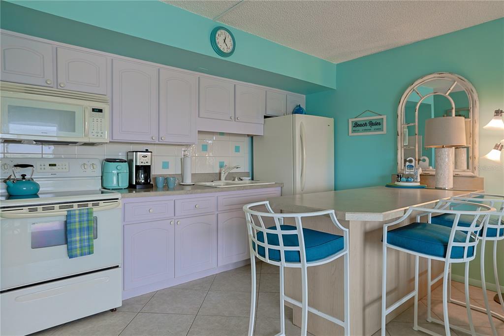 3700 South Atlantic Avenue, Unit 414 New Smyrna Beach, FL 32169 - Photo 13 of 30 a kitchen with stainless steel appliances granite countertop a table chairs and a refrigerator
