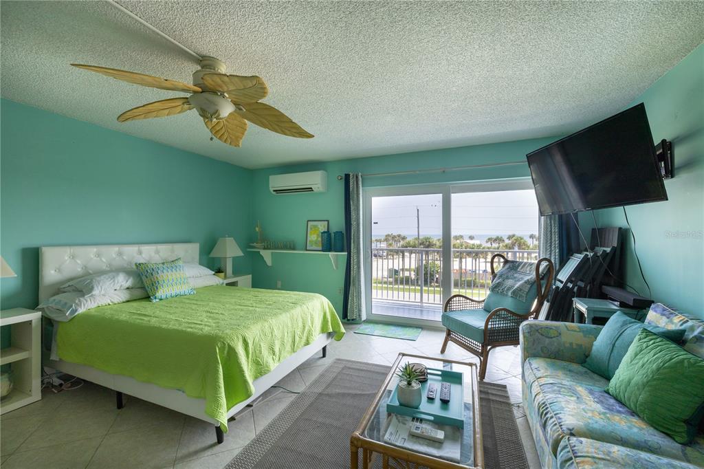 3700 South Atlantic Avenue, Unit 414 New Smyrna Beach, FL 32169 - Photo 26 of 30 a bedroom with a bed a couch and a flat tv screen