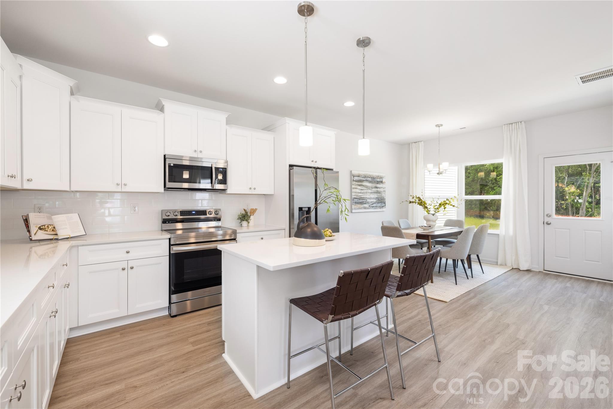 5514 Anderson Road Charlotte, NC 28269 - Photo 16 of 20 a kitchen with stainless steel appliances kitchen island granite countertop a stove a sink a dining table and chairs with wooden floor