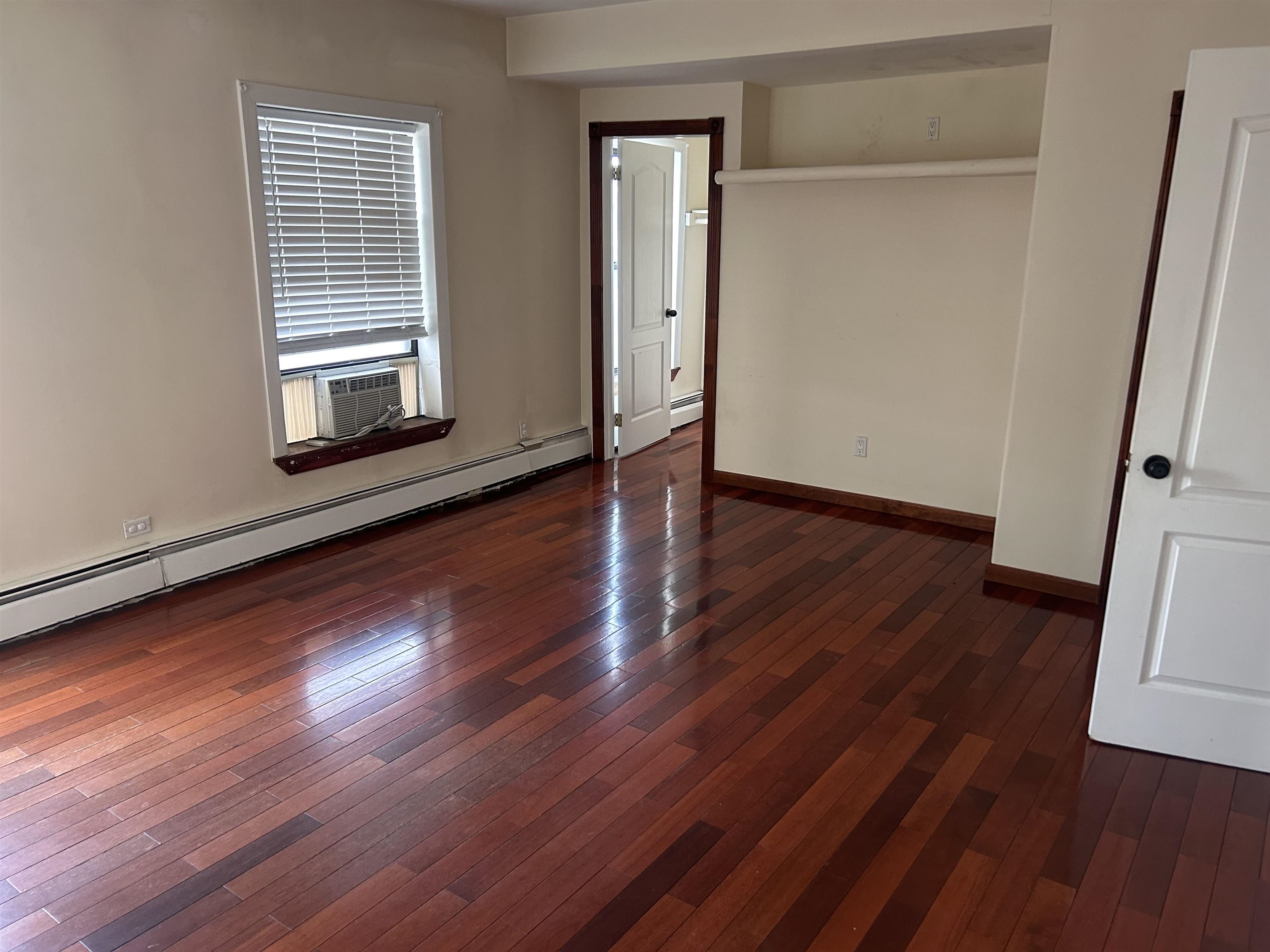 236 Grove Street Jersey City, NJ 07302 - Photo 4 of 7 an empty room with wooden floor and windows