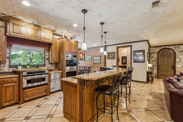 a kitchen with stainless steel appliances a stove a sink a oven a dining table and chairs with wooden floor